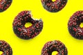 Black bited donuts with red glaze on yellow background seamless pattern top view. Food dessert flatly flat lay of