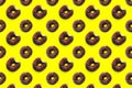 Black bited donuts with red glaze on yellow background seamless pattern top view. Food dessert flatly flat lay of