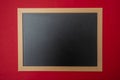 Black blank empty blackboard with wooden frame, red wall background, copy space Royalty Free Stock Photo