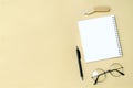 Black blank notebook, pen, glasses, goggles, flash drive top view on beige background. Top view desk arrangement. Time