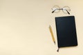 Black blank notebook, pen, glasses, goggles top view on beige background. Top view desk arrangement. Time management, planning
