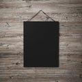 Black blank poster hanging on leather belt on wood background