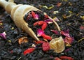 Black blended tea with flower petals and dried fruit on a wooden spoon. close up Royalty Free Stock Photo