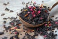 Black blended tea with flower petals and dried fruit on a wooden spoon. Royalty Free Stock Photo