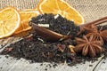 Black blended tea with flower petals and dried fruit in wooden spoon on wooden desk. Black tea, anise stars and dried oranges Royalty Free Stock Photo