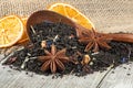 Black blended tea with flower petals and dried fruit in wooden spoon on wooden desk. Black tea and dried oranges Royalty Free Stock Photo