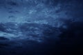 Black blue night sky with clouds. Dark dramatic sky background. Storm, rain. Frightening, ominous atmosphere.