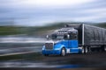 Black and blue stylish big rig semi truck transporting commercial cargo in covered black semi trailer Royalty Free Stock Photo