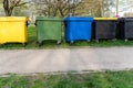 Black, blue, yellow, green garbage recycling bins on street in city. Segregate waste, sorting garbage.