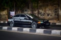 Black BMW 325i E46 sedan driving fast on the road blurry in motion