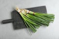Black board with bunches of green onions on grey stone table Royalty Free Stock Photo