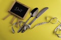 Black Board, spoon and knife  with a measuring tape, diet or healthy eating concept Royalty Free Stock Photo