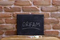 Black board with the word DREAM drown by hand on wooden table on brick wall background Royalty Free Stock Photo