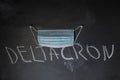 On the black board is written in chalk Deltacron. Above the word hangs a medical mask. Deltacron New variant of the SARS