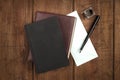 A black book, a leather journal, a blue envelope, and an ink well and pen
