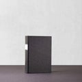 Black book with white frame on spine standing on dark surface Royalty Free Stock Photo