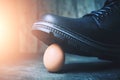 Black boot steps on a fragile chicken egg. Concept, weak defenseless, care and custody