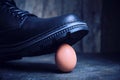 Black boot steps on a fragile chicken egg. Concept, weak defenseless, care and custody Royalty Free Stock Photo