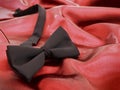 Black bow tie against red satin background Royalty Free Stock Photo