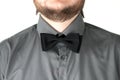 Black bow-tie with gray shirt on men's neck.