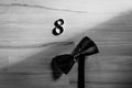 Black bow-tie and wedding rings lying in the form of a number eight on wooden background Royalty Free Stock Photo