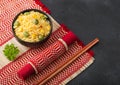 Black bowl with boiled organic basmati vegetable rice with wooden chopsticks on red bamboo placemat. Yellow corn and green peas