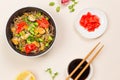 A black bowl of buckwheat soba noodles with seafood and vegetables. Flatlay on a light background with soy sauce and Royalty Free Stock Photo