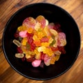 Black bowl with colorful sweet candy like gummibears on a wooden plate Royalty Free Stock Photo