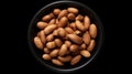 Photo of a black bowl filled with almonds on a black background