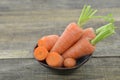 Black bowl with fresh carrots and cut on wooden table, closeup Royalty Free Stock Photo