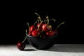 Black bowl full of ripe cherries on gray marble table with black background Royalty Free Stock Photo