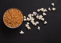 Black bowl with raw sweet corn and popcorn on wood