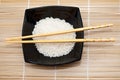 Black bowl with rice and chopsticks