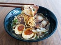 A black bowl of Shoyu Ramen noodles with pork and eggs on wooden table Royalty Free Stock Photo