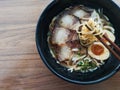 A black bowl of Shoyu Ramen noodles with pork and eggs on wooden table Royalty Free Stock Photo