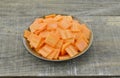 Black bowl with thin slices carrots on wooden table Royalty Free Stock Photo