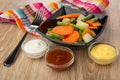 Black bowl with vegetable mix, napkin, bowls with sauces