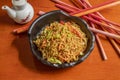 Black bowl with vegetable noodles with sauteed carrot, chopped chives, spring onion and onion and soy sauce