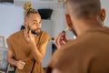 Black Brazilian gay applying make up eyeshadow looking mirror