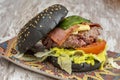 black bread burger with sesame seeds a good piece of minced beef, bacon, cheese and fried green peppers with lettuce