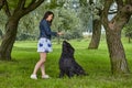 Black Briard dog has training outdoor with woman.