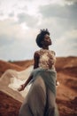 Black bride in long wedding dress and bridal veil stands on background of beautiful landscape. Royalty Free Stock Photo