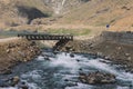 Black Bridge through the River Water Flow with Rocks in Gilgit Baltistan Highlands Royalty Free Stock Photo