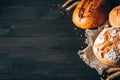 Black and brown breads with spikelets on wooden background with copy space. Three different types of bread on the right Royalty Free Stock Photo