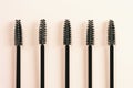 Black brushes and applicators for eyelashes and eyebrows on yellow background.