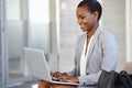 African american woman working on laptop sitting on sofa Royalty Free Stock Photo