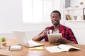 Black businessman in casual office, reading news on tablet, drinking coffee Royalty Free Stock Photo