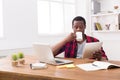 Black businessman in casual office, reading news on tablet, drinking coffee Royalty Free Stock Photo