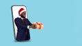 Black Businessman In Santa Hat With Gift Peeking Out Of Big Smartphone