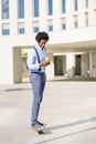 Black businessman on a skateboard looking at his smartphone outdoors.